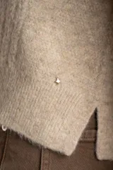 Sweater de punto color beige melange, con cuello redondo y manga larga. Presenta un tejido texturado con relieve vertical.