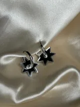 Par de aros dorados con forma de estrella negra.