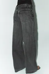 Jeans de tiro alto con pierna ancha y largo completo. Confeccionados en tejido rígido con cinco bolsillos, cintura con trabillas, detalle de costuras torcidas y cierre con cremallera y botón metálico.