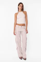Pantalón cargo color arena de corte recto y tiro bajo, con recortes y presillas dobles en la cintura. Tiene acceso mediante cierre de nylon y botón personalizado, seis bolsillos laterales y dos en la espalda con tapa y botón snap a presión.