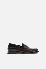 Mocasín de vestir color marrón oscuro con estampado de cocodrilo, horma redonda y suela con ligero tacón.