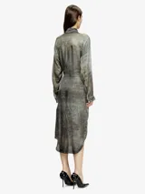 Vestido largo tipo camisa, color gris oscuro con efecto desgastado/decolorado, manga larga y cuello camisero. La prenda se anuda a la altura de la cintura, creando un efecto drapeado asimétrico en la falda.