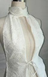 Top blanco con textura, cuello halter y abertura en el frente.
