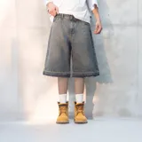 Bermuda de jean gris oscuro con efecto desgastado, corte amplio, largo a la rodilla y ruedo desflecado.