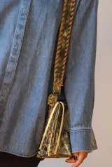 Bandolera de cuero verde con estampado animal print dorado y correa de cuero trenzada.