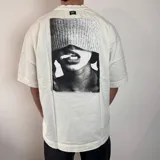 Remera color crema de corte oversize con estampado en la espalda de una mujer fumando y un gorro de lana.