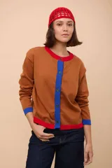 Saco marrón de algodón con cuello redondo, cierre frontal con botones azules, mangas largas con puños azules y ribete rojo en cuello y ruedo.