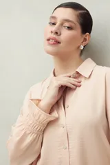 Camisa negra de manga larga con cuello clásico y botones frontales. El tejido presenta una textura arrugada o plisada, y los puños tienen un detalle fruncido o elástico.