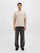 Remera color crema de corte recto y mangas cortas, con cuello redondo. Estampado en la espalda con un dibujo de una calle con edificios, palmeras y un auto amarillo.