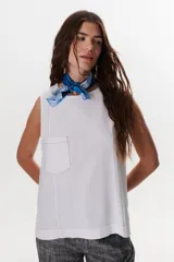 Top sin mangas color terracota con cuello redondo y bolsillo frontal. Presenta costuras a contratono en blanco que definen los bordes y el bolsillo.