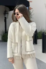Chaqueta corta color gris oscuro confeccionada en lana merino hervida, con cuello redondo, mangas largas y bolsillos frontales. Presenta detalle de flecos en el ruedo.