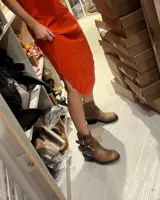 Bota corta de cuero vacuno color marrón claro, con hebillas metálicas y suela de goma negra.