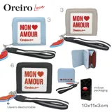 Billetera celeste con cierre perimetral, detalle de placa con la inscripción 'Mon Amour' y llavero con forma de labios.