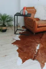 Alfombra de cuero marrón con manchas blancas.