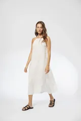 Vestido midi blanco de lino, con breteles finos elásticos regulables en la espalda y corte holgado.