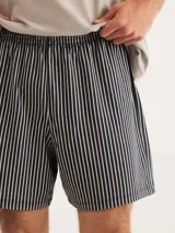 Conjunto de pijama para hombre compuesto por una remera azul marino de manga corta con cuello en V y un short a cuadros en tonos azul, gris y blanco.