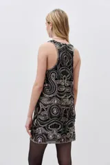 Vestido corto negro con cuello redondo y sin mangas, completamente bordado con mostacillas, piedras y lentejuelas. Tiene corte recto y calados que acompañan el diseño.