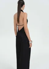 Top negro satinado con escote halter, espalda descubierta y bajo asimétrico.