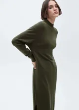 Vestido midi color verde militar, de tejido de punto fino, cuello alto y manga larga. Diseño recto y holgado con aberturas laterales en el ruedo.