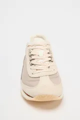 Zapatillas deportivas tipo running, color gris claro con detalles en beige y blanco. Combinación de materiales en el corte y suela en contraste. Cierre mediante cordones de color.