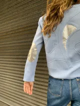 Cárdigan celeste tejido en lana con apliques de cuero y cintas tejidas.