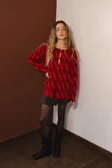 Cárdigan tejido con diseño de rombos rojos y negros, con mangas largas y cierre frontal con botones.