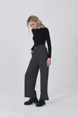 Pantalón de tiro alto, corte recto y largo, con estampado de lunares blancos sobre fondo negro.