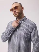 Camisa de manga larga a rayas verticales azules y blancas, con cuello abotonado y bolsillo en el pecho. Confeccionada en lino y algodón.