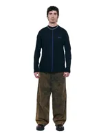 Pantalón unisex de denim 100% algodón con acabado marmolado color bronce. De tiro medio y calce wide/relajado, con pierna muy amplia y caída larga. Cintura con elásticos laterales, costuras curvas y bolsillos delanteros y traseros con bocas redondeadas.