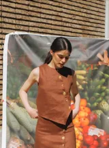 Top marrón de lino con cartera asimétrica y botones de madera. Tiene ojales bordados con frutitas.