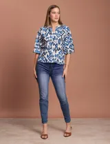 Blusa blanca de gasa marca Sioni, con cuello a la base y escote en V. Tiene abertura central con botones y mangas 3/4 con terminación fruncida.