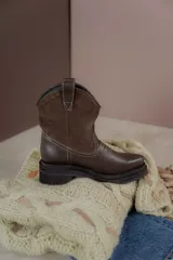 Bota corta de cuero marrón con puntera redondeada, caña alta con detalle de gamuza y costuras decorativas.