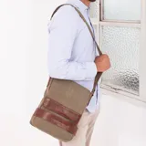 Morral matero de lona color gris con detalles en cuero marrón. Tiene tapa con broches magnéticos, bolsillo tipo guantera bajo la tapa, división interna con velcro desmontable, bolsillo trasero con broche magnético y correa larga regulable.