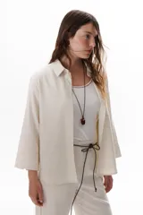 Camisa verde militar de manga larga con puños color crema, cuello clásico y cierre frontal con botones. Tiene un bolsillo en el pecho con bordado de una palmera color crema.