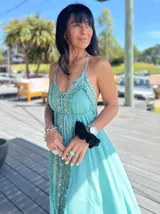 Vestido largo rosado con breteles finos y abertura frontal. Presenta bordados y lentejuelas a lo largo del frente.