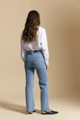 Jean de corte recto y tiro medio, color gris oscuro con efecto lavado. Presenta apliques de tachas metálicas pequeñas en la zona de los bolsillos delanteros.