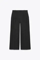 Pantalón negro de tiro alto con trabillas, bolsillos laterales y pinzas. Cierre frontal con cremallera, botón interior y gancho metálico.