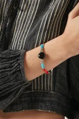 Pulsera elástica con tres hilos de cuentas de vidrio rojas y celestes, separadas por cuentas plateadas con diseño calado.