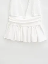 Top blanco con escote halter, espalda descubierta y volado en el ruedo.