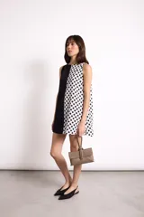 Vestido corto sin mangas, con panel frontal blanco con lunares negros y panel lateral negro.