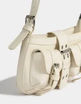 Cartera baguette color crudo de cuerina con correa regulable y hebillas frontales decorativas.