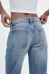 Pantalón de jean celeste de corte recto y tiro bajo, con cinco bolsillos y cierre frontal con cremallera y botón metálico.