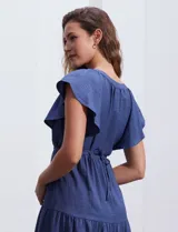 Vestido midi celeste de poliéster, con cuello a la base y escote en V. Presenta cintura con frunces y lazo de ajuste, mangas ranglan con sisa amplia y falda escalonada. Marca Emma & Michele.