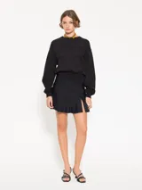 Minifalda negra confeccionada en lycra doble, con cierre lateral y tiracierre en tela base. Tiene doble capa de volados caracol en el ruedo y tajo con moño en tela complemento.