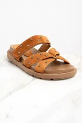 Sandalias marrones de gamuza con apliques de tachas doradas, con dos tiras anchas sobre el empeine y suela plana.
