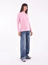 Polera rosa de tejido canalé, con cuello alto y mangas largas.