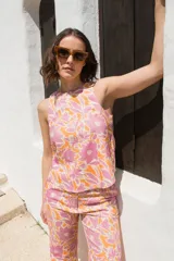 Top sin mangas con estampado floral en tonos rosados y naranjas, con cuello redondo y espalda descubierta atada con tres lazos.