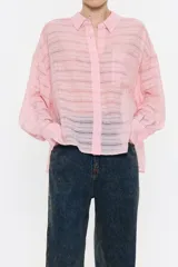 Camisa rosa con rayas horizontales, de corte holgado, manga larga con puños abotonados, cuello camisero, cierre frontal con botones, bolsillo de parche en el pecho y canesú en la espalda con pliegue.