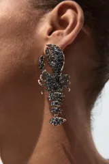 Par de aros colgantes con forma de langosta, con apliques de brillantes en tono gris oscuro. Cierre con tuerca y clip.