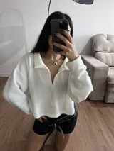 Buzo blanco de tejido de punto con cuello polo y mangas largas.